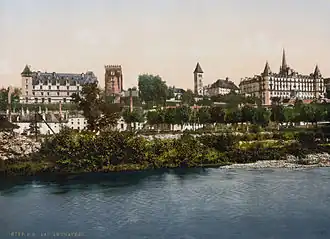 Photographie en couleurs représentant divers bâtiments surplombant un cours d'eau.