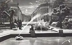 photographie en noir et blanc d'une fontaine et d'une statue, avec des montagnes en arrière plan.
