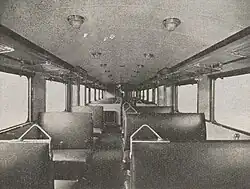 Photographie en noir et blanc montrant l'intérieur de l'autorail avec plusieurs rangées de sièges alignés.