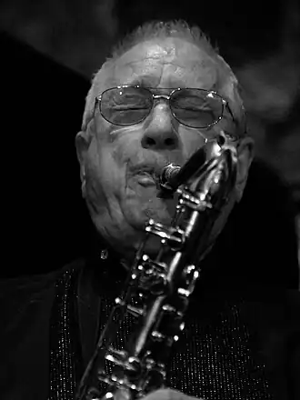 Photo noir et blanc, en gros plan, d'un homme jouant du saxophone.