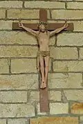 Sur un mur de pierre, bois peint représentant Jésus en croix.