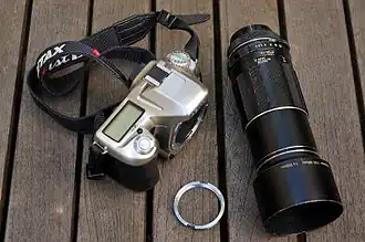 Montage d'un objectif M42 à vis Takumar 4/200 sur un reflex numérique Pentax à l'aide d'une bague adaptatrice, au centre.