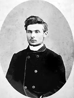 Photographie en noir et blanc et en médaillon d'un jeune homme portant un manteau.
