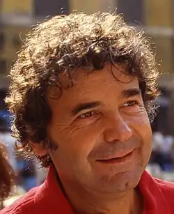 Un homme aux cheveux frisés, souriant.