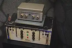 Boîtier métallique avec plusieurs boutons surmonté d'un autre plus petit boîtier.