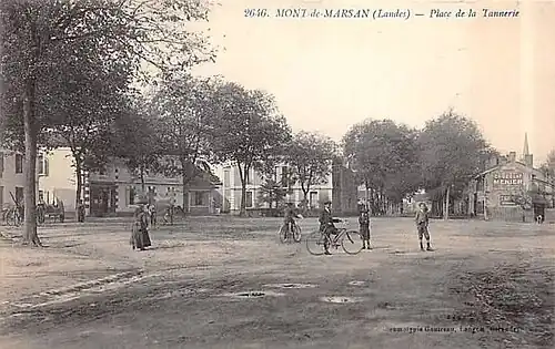 Ancienne place de la Tannerie, non encore pavée ou goudronnée. Le clocher de l'église de Saint-Jean-d'Août est visible en arrière-plan.
