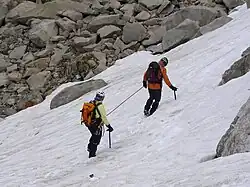 Deux alpinistes encordés progressant sur une pente de neige, corde tendue