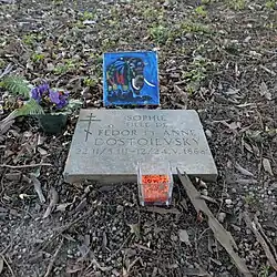 Petite plaque en pierre ; en haut, un dessin et une fleur.