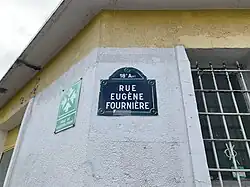 mur blanc de coin d'une maison avec une plaque de rue, photographié en contre-plongée