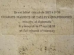 Photo d'un mur de grandes pierres blanches finement jointes, dont une au centre est gravée par les lignes suivantes : « En cet hôtel vécut de 1812 à 1838 / CHARLES-MAURICE DE TALLEYRAND-PERIGORD / ministre et diplomate / Il y mourut le 17 mai 1838 / et fut inhumé à Valençay ».
