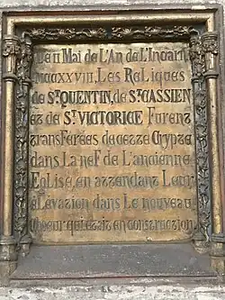 Plaque de bronze gravée et incrustée dans un mur en pierre.