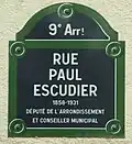 Plaque de tôle émaillée conforme à la réglementation de 1982. Un court texte indique l'origine du nom ou présente le personnage honoré