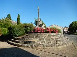 Vue du monument appelé « calvaire » : une croix de pierre, au sommet d'un cercle de pierre taillé en escaliers et orné de fleurs.