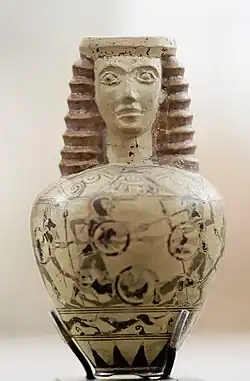 Aryballe au buste féminin; combat de hoplites; chasse au lièvre. H. 7,2&nbsp;cm. Protocorinthien récent PCR, v. 650-630. Louvre