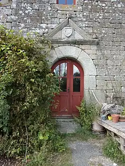 Porte que surmonte un fronton triangulaire timbré d'un écu.