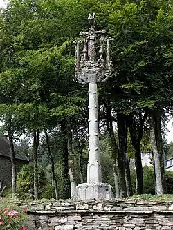 Photographie d'un calvaire en granite avec des arbres derrière