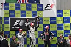 Photo du podium du GP d'Espagne, avec Button entouré de Barrichello et Webber, applaudis par les officiels de l'épreuve
