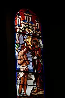 Photographie couleur d'un vitrail montrant le baptême de Jésus par Jean-Baptiste.