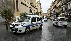 Photographie de deux voitures de police dans une rue piétonne.