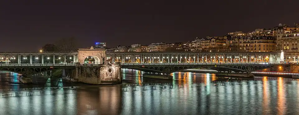 Nombreuses petites lumières partout, des arches plongent dans l'eau, soutenant une colonnade. Ces lumières se reflètent dans l'eau du fleuve, lui donnant une lumière bleue dans la nuit.