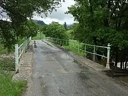 Pont à rambarde en fer forgé aux extrémités en forme de balustres.