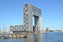 Bâtiment moderne en forme d'arche au-bord de l'eau.