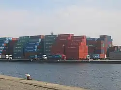 Photographie prise sur le port représentant des conteneurs empilés les uns sur les autres