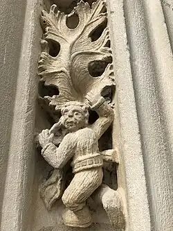 Sculpture d'un petit homme escaladant une feuille de vigne.