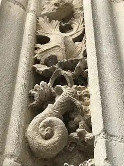 Sculpture d'un coquillage en dessous d'une feuille de vigne.