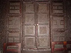 Photographie de la porte à deux battants de la maqsura. Chaque vantail possède quatre panneaux ajourés de forme carrée.