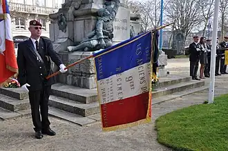 Porte-drapeau du 9e&nbsp;régiment de chasseurs parachutistes devant le monument aux morts de Laval (mars 2012).