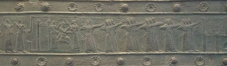 Le roi chef de guerre : Salmanazar III (858-824 av. J.-C.) d'Assyrie sur son trône observe ses troupes à l'assaut d'une ville ennemie. Portes de Balawat (British Museum).