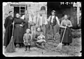Portrait de famille ou groupe de travailleurs agricoles dans une cour de ferme, avec un prêtre, Val-d'Izé