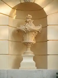 Une sculpture dans une niche, sur une façade de couleur jaune.