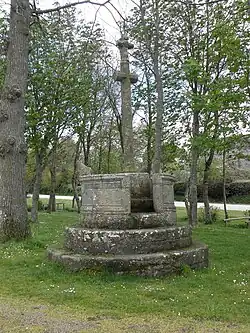 Petit calvaire à trois marches avec simplement le Christ en croix. En haut des marches, une chaire circulaire entoure la croix. Un pupitre en pierre est posé sur le rebord.