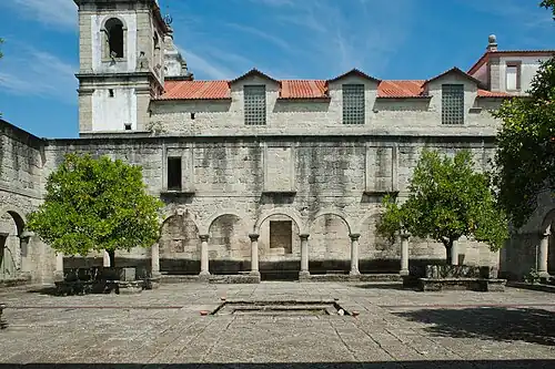 Photographie d'un cloître situé devant une église vue latéralement.