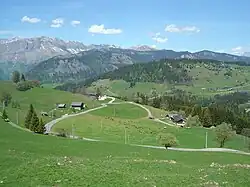 Prairies et fermes au niveau du lieu-dit « Les Molliettes ». Au fond la chaîne des Aravis.