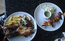 À gauche : homard tandoori avec frites et légumes. À droite : crevettes tandoori avec sauce.