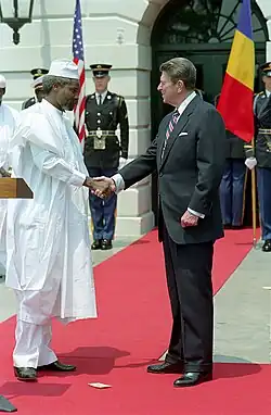 Deux hommes se serrent la main sur un tapis rouge