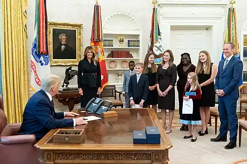 Amy Coney Barrett et sa famille (à l'exception de son plus jeune fils) dans le Bureau ovale (2020), en présence de Donald et Melania Trump.