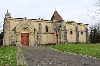 église romane de pierre blonde au toit de tuile avec un portail