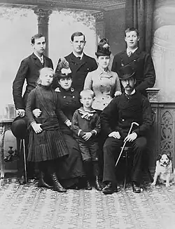 Photographie noir et blanc d'une famille de huit personnes accompagnée d'un chien.