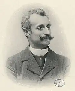 Photo en noir et blanc d'un homme moustachu, de buste.