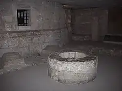 Photo du puits de l'œuvre situé dans la chapelle absidiale et une niche engrillagée dans le mur, qui contient le coffret de plomb renfermant le cœur du roi de France Charles V, retrouvé lors des fouilles de 1931