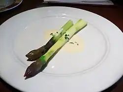 Deux asperges produites à Lauris, dans le Vaucluse, présentées sur la même assiette avec une sauce au beurre blanc