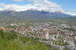 Photos d'immeubles d'habitation et commerciaux avec en arrière plan des montagnes partiellement enneigées prise depuis un point dominant.