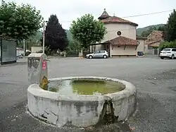 Place centrale du village avec un abreuvoir et l'église Saint-Jean-Baptiste en arrière plan