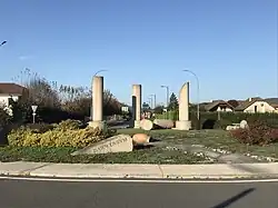 Photographie en couleurs représentant trois colonnes érigées sur un rond-point.