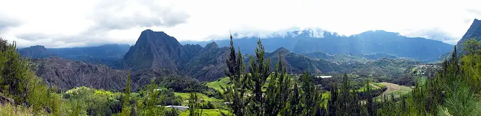 Vue panoramique d’un paysage montagneux et verdoyant.