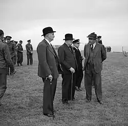 Photographie en noir et blanc d'un groupe d'hommes debout et en discussion.
